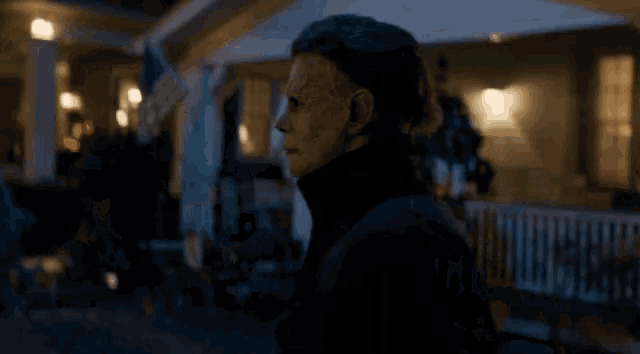 a person with a mask on standing in front of a house