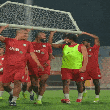 a group of soccer players wearing red jerseys with ucb on them