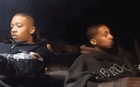 two men are sitting in a car and one of them is wearing a hoodie that says bro on it .