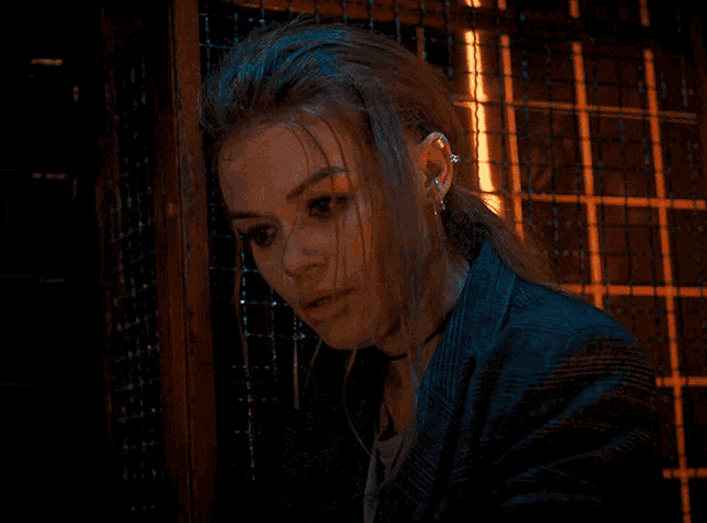 a woman with a piercing in her ear is leaning against a fence