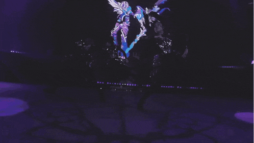 a group of people are dancing on a stage with a large screen behind them