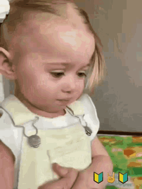 a little girl wearing overalls and a white shirt is looking down