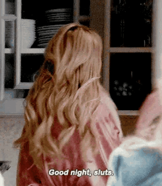 a woman with long blonde hair is sitting in a kitchen talking to another woman .