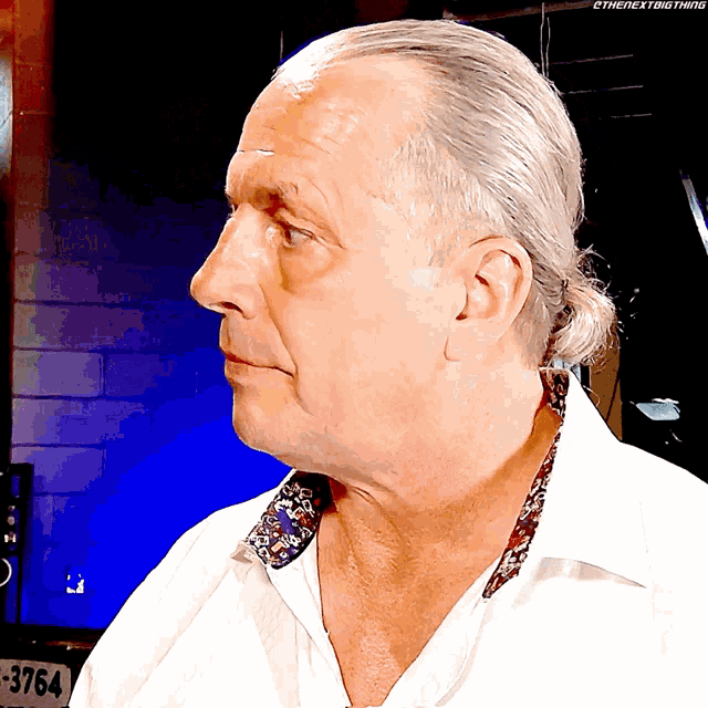 a man wearing a white shirt with a floral collar has the number 3764 on the back of his shirt