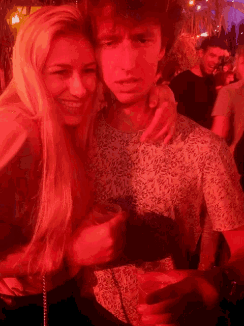 a woman is hugging a man who is holding a cup