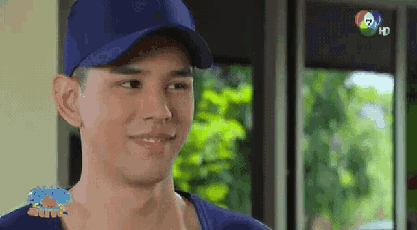 a man wearing a blue hat is smiling in front of a window that says hd on it