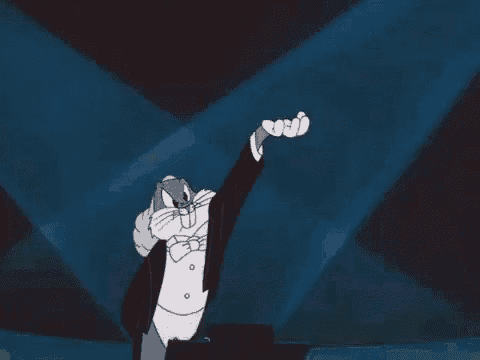 bugs bunny is wearing a tuxedo and bow tie while playing a piano on a stage .