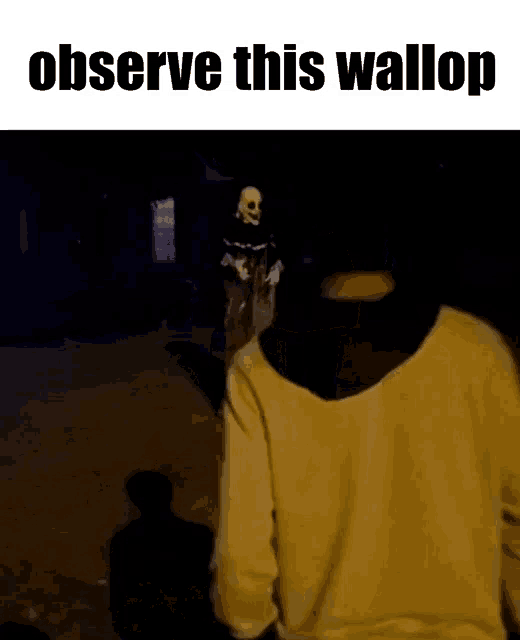 a man in a yellow sweatshirt is standing in front of a skeleton statue that says observe this wallop ..