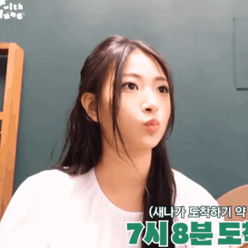 a woman making a funny face in front of a green sign that says 7 8