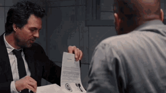 a man in a suit and tie is holding a piece of paper with a picture of a man on it .
