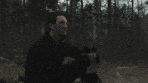 a man in a black shirt is holding a gun in his hand