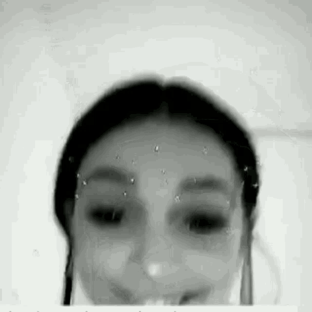 a black and white photo of a woman 's face with water drops on her face .
