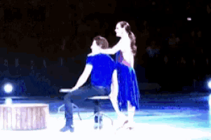 a man and a woman are sitting on a chair on a stage