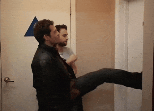 two men are standing next to each other in front of a door with a blue triangle on it
