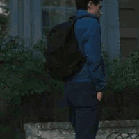 a man wearing a blue jacket and a backpack is standing in front of a building