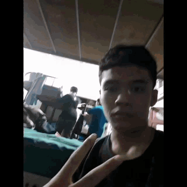 a young man is making a peace sign in front of a group of people .