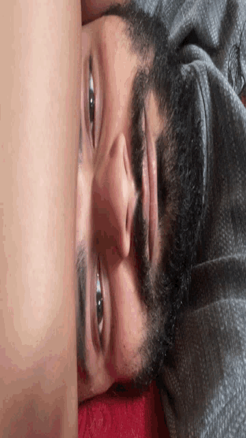 a man with a beard is laying down with his head resting on another person 's arm
