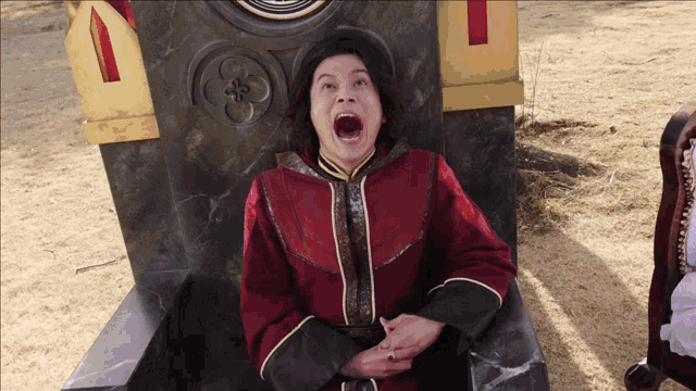 a man in a red coat is sitting in a chair with his mouth wide open