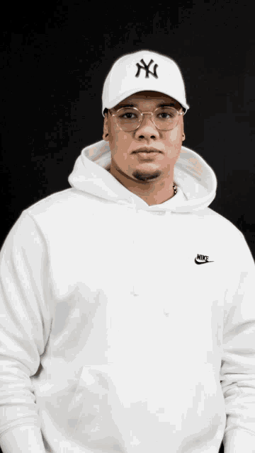 a man wearing a ny yankees hat and a nike hoodie