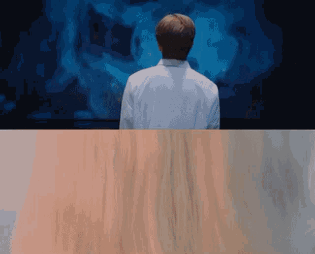 a man in a white shirt is standing in front of a screen