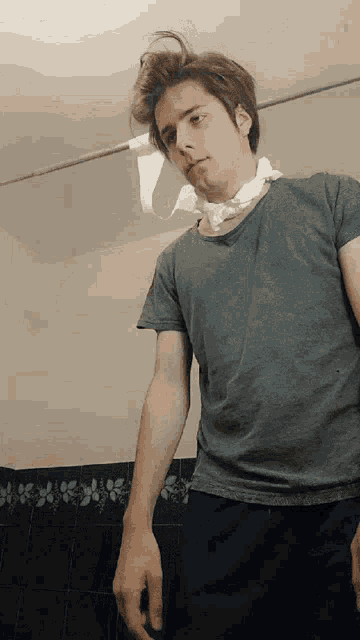 a man in a grey shirt has a piece of toilet paper hanging from his neck
