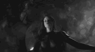 a black and white photo of a person holding a gun in a dark room .