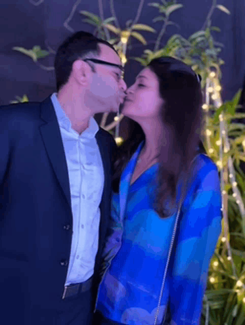a man kissing a woman on the cheek in front of a tree