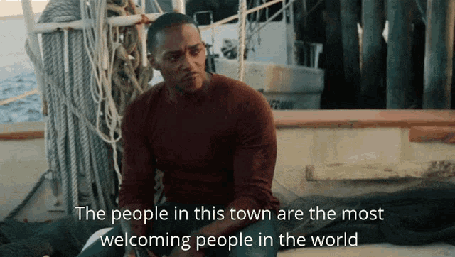 a man sits on a boat with the words " the people in this town are the most welcoming people in the world " below him