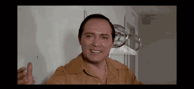 a man in a brown shirt is making a face