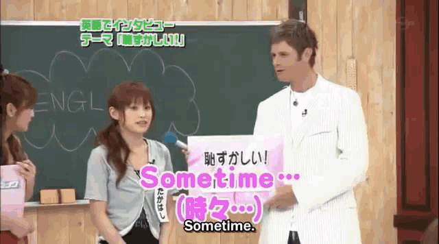 a man stands next to a woman holding a sign that says " sometime "