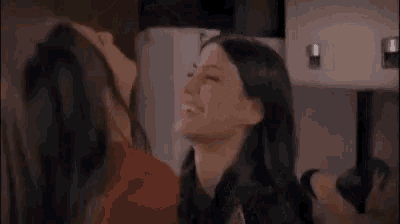 two women are looking at each other and smiling while standing next to each other .