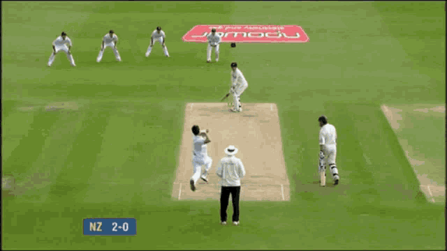 a man in a white shirt stands in front of a crowd with nz 2-1 written on the screen