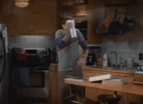 a man is standing in a kitchen holding a remote control in his hand