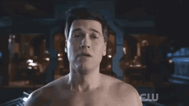 a shirtless man stands in front of a sign that says cw on it