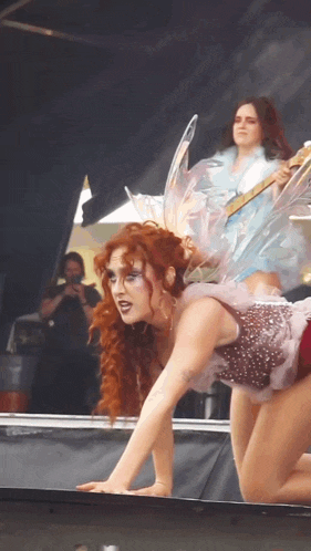 a woman in a fairy costume is crawling on a stage