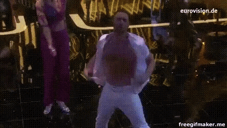 a man without a shirt is singing into a microphone with eurovision.de written on the bottom right