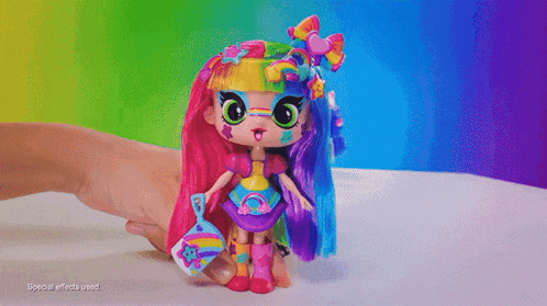 a person is holding a doll with a rainbow hairdo
