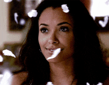 a woman is smiling with feathers falling around her