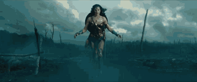 a woman in a wonder woman costume is walking through a field with her arms outstretched .