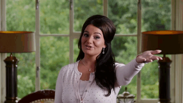 a woman is standing in front of a large window with her arm outstretched
