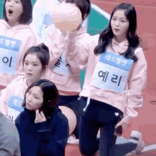 a girl in a pink hoodie is kneeling down while another girl holds a balloon in her hand .