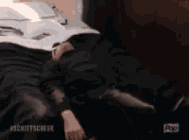 a person laying on a bed with the hashtag schittscreek on the bottom