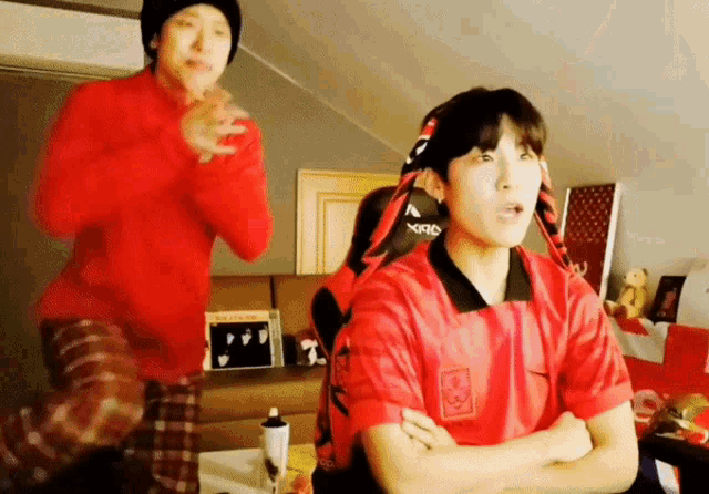 a man in a red shirt with a chinese symbol on it stands next to another man in a red shirt