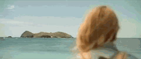 a woman is looking out over the ocean at a small island