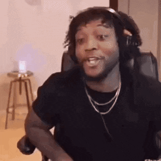 a man wearing headphones and a necklace is sitting in a chair making a funny face .