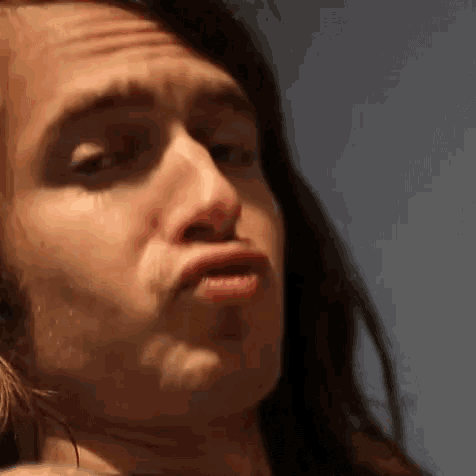 a close up of a man with long hair making a funny face .