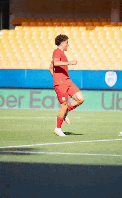 a soccer player kicks a ball on a field with a sign that says uber eats