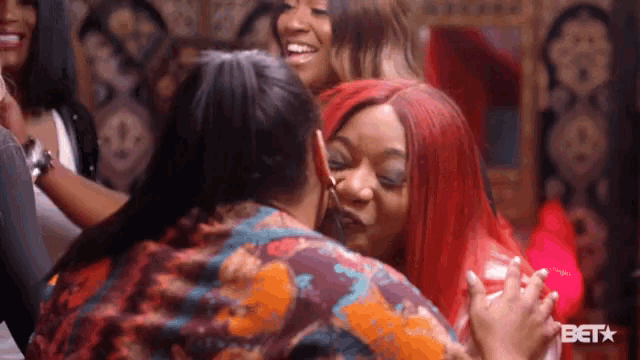 a woman with red hair is kissing another woman in front of a bet sign