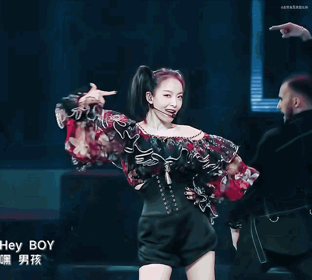 a woman in a ponytail stands on a stage with chinese writing on the bottom right