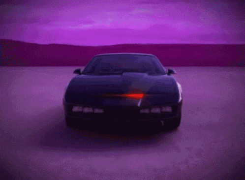 a black car is driving down a road with a purple sky behind it